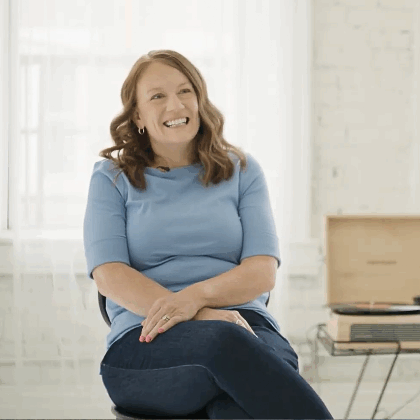 Cincinnati DBT Social Worker Christina Huster sits with arms crossed smiling at the camera with white background, discussing her love for working with kids and teens
